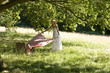 A young woman laying a picnic blanket on the grass