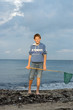 Junge mit einem Kächer am Meer im Sonnenlicht
