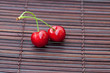 two cherries on a bamboo mat two cherries on a bamboo mat