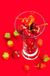glass of cherry and strawberry on a red background glass of cherry and strawberry on a red background