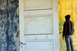 Hooded figure in abandoned house. Torn wallpaper.
