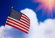 American toy flag over blue cloudy sky.