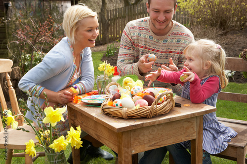 Foto: Family Decorating Easter Eggs On Table Outdoors Family Decorating Easter Eggs On Table Outdoors
