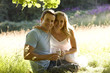 A young couple sitting on the grass, drinking wine