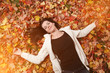 Portrait of beautiful young woman lying on yellow autumn leaves Portrait of beautiful young woman lying on yellow autumn leaves