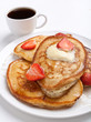 stack of pancakes with syrup, butter and strawberries