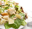 traditional caesar salad on white plate with a fork