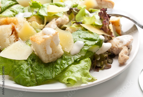 Photo: traditional caesar salad on white plate with a fork traditional caesar salad on white plate with a fork
