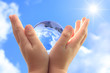 Globe on child hand against blue sky, serie.