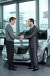 Car salesperson shaking hands with customer at showroom
