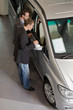Car salesperson showing young man new car at showroom