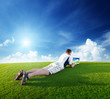 Young man use a notebook on green field