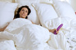 Young woman holding dildo on bed