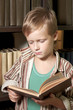 The boy reads the book with a serious face.