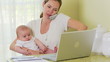 Mother working on laptop with baby
