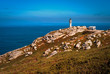 Seascape with a lighthouse over the rocks and a blue sky
