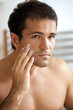 Reflection of young man in mirror applying shaving cream