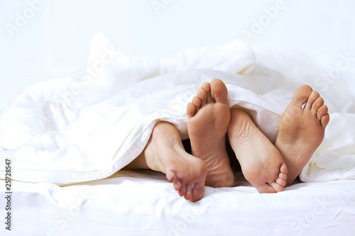 Photo: Close-up of the feet of a couple on the bed Close-up of the feet of a couple on the bed