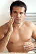 Reflection of young man in mirror applying shaving cream