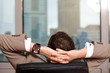 Businessman relaxing in office, rear view
