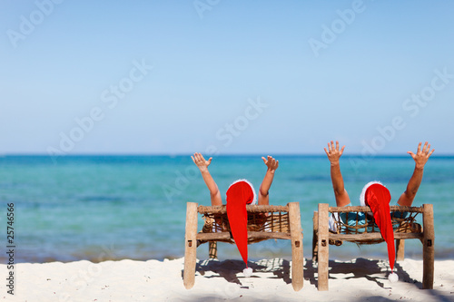 Photo: Couple in Santa hats on tropical beach Couple in Santa hats on tropical beach