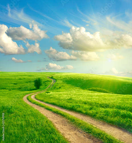 Photo: Summer landscape with green grass, road and clouds Summer landscape with green grass, road and clouds