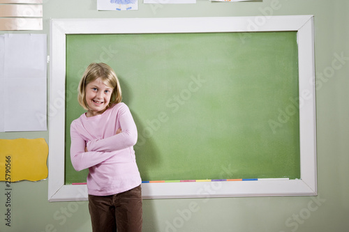 Photo: School girl in classroom standing by blackboard School girl in classroom standing by blackboard
