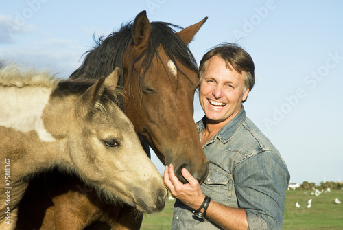 Photo: Man petting his horses. Man petting his horses.