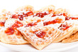 Stack of waffles in shape of heart with strawberry jam and sugar