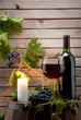 red wine bottle and glass with a candle background