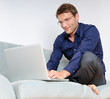 Young man relaxing with laptop on a couch