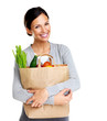 Happy young female holding a shopping bag full of groceries