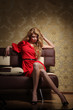 Glamour woman in red dress on sofa in luxury retro interior