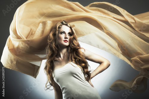 Foto: Portrait of the young woman against a flying fabric Portrait of the young woman against a flying fabric