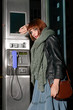 Photo: young woman standing at a phonebox young woman standing at a phonebox