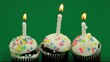 Three birthday cupcakes with candles burning