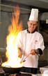 Professional cook preparing food on flame.