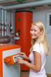 Frau im bei Heizung im Heizungskeller. Energie sparen