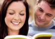 Close-up of a smiling couple of students reading a book Close-up of a smiling couple of students reading a book