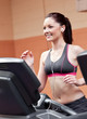 Smiling athletic woman training on a running machine with earpho