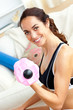 Smiling athletic woman holding a dumbbell in her living-room