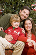 Photo: Family with boy sitting in front of Christmas tree Family with boy sitting in front of Christmas tree