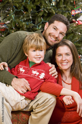 Photo: Family with boy sitting in front of Christmas tree Family with boy sitting in front of Christmas tree