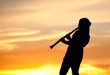 A silhouetted woman plays the Clarinet at sunset.