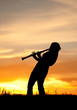 A silhouetted woman plays the Clarinet at sunset.
