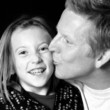 proud daddy kissing daughter in black and white