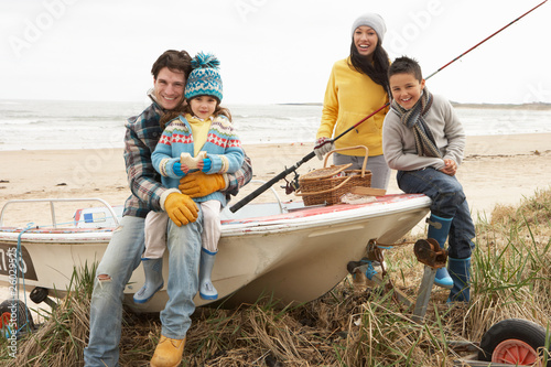 Photo: Family Group Sitting On Boat With Fishing Rod On Winter Beach Family Group Sitting On Boat With Fishing Rod On Winter Beach