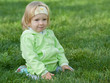 Portrait of a pretty little girl in green in the green grass