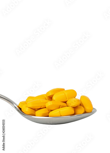 Photo: Ein ganzer Löffel voller gelber Tabletten freigestellt Ein ganzer Löffel voller gelber Tabletten freigestellt
