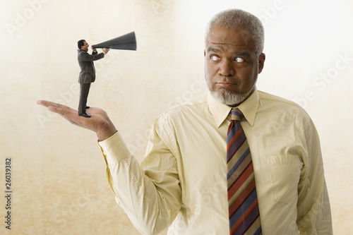 Photo: Miniature businessman speaking with bull horn to giant businessman Miniature businessman speaking with bull horn to giant businessman